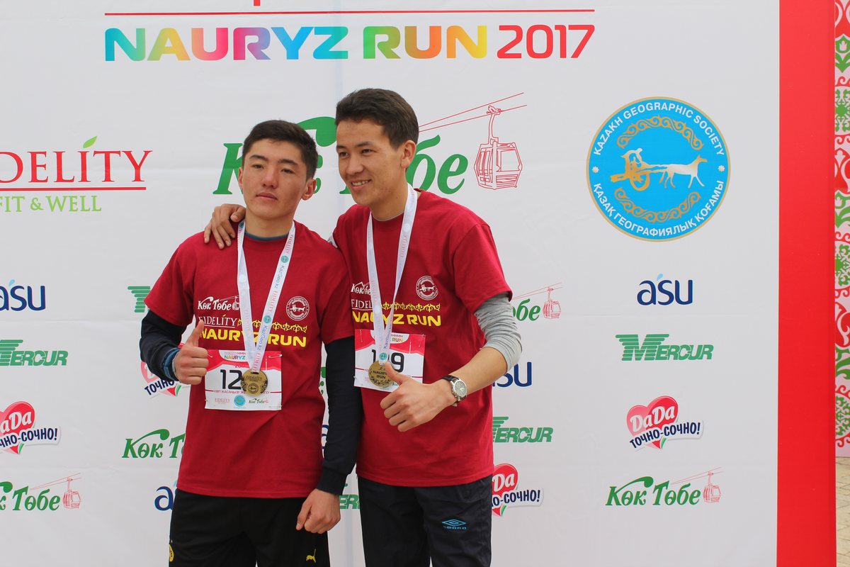 Финишировавшие участники с медалями на фоне баннера Nauryz Run, Кок-Тобе и Fidelity